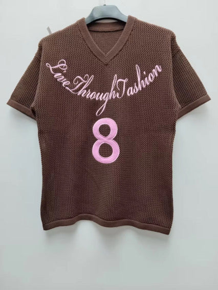 Short sleeve knit v-neck sweater in deep chocolate brown with pink logo ￼ embroidered with lucky number 8      The number 8 symbolizes infinity,   balance, and abundance, stemming from its infinite shape.